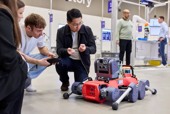 Group of people observing and interacting with a robotic device in a technology setting