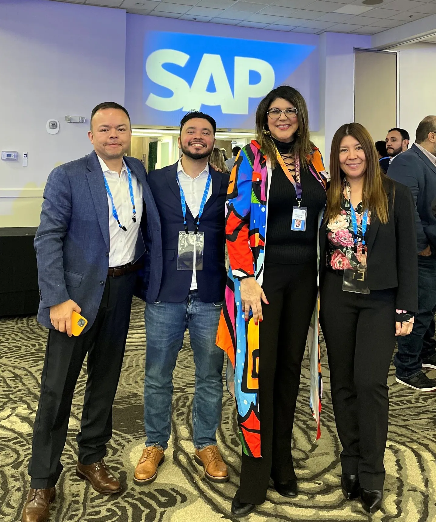 Michelle, second from right, stands with three colleagues beneath an SAP logo at an event.