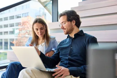 Two people collaborating on a laptop in a modern workspace