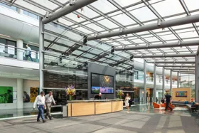 Modern office lobby with a reception desk, large screen, and glass architecture