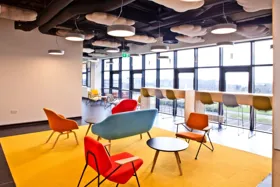 Modern office lounge area with colorful chairs and a yellow rug
