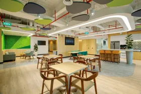Modern office interior with seating areas, tables, and green wall accents