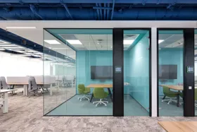 Modern office meeting rooms with glass walls and green chairs