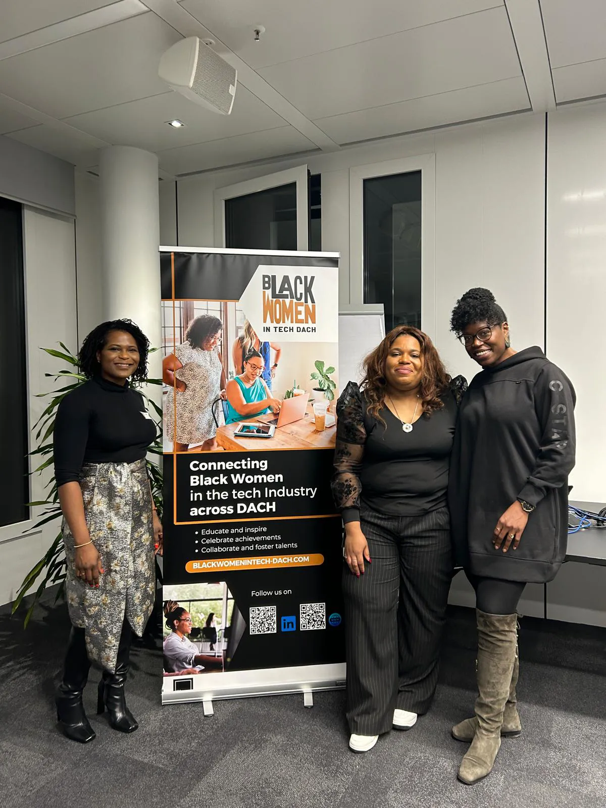 Chioma posing with two attendees beside a Black Women in Tech banne