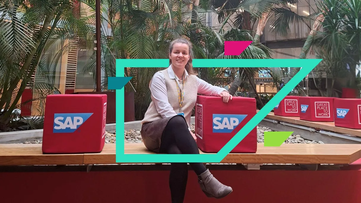 Person sitting on a bench with SAP-branded cubes in a green indoor space