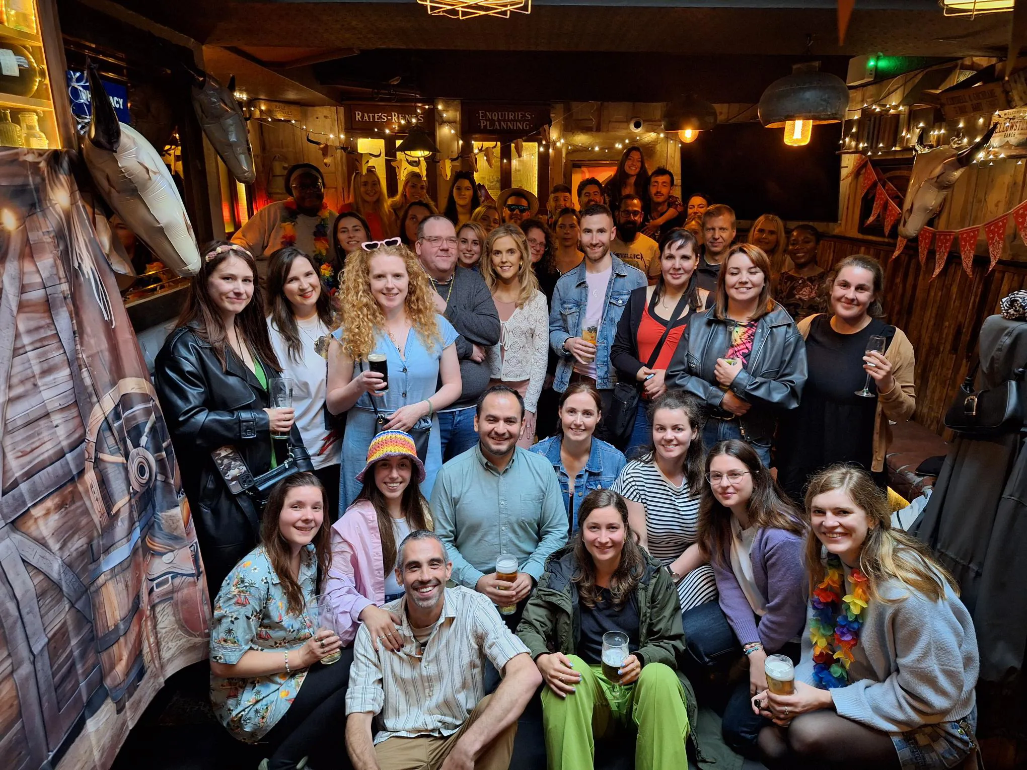 Emma posing with a large group of colleagues at an indoor social gathering.