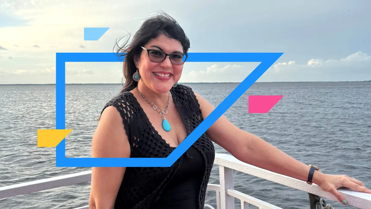 Woman smiling on a boat with a body of water in the background