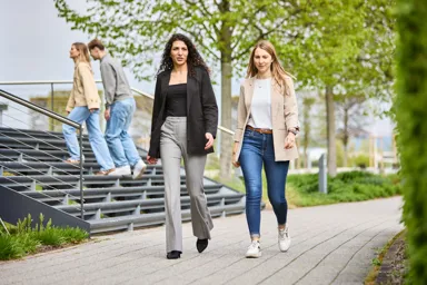 Two women walking on a pathway while two men walk up stairs in the background