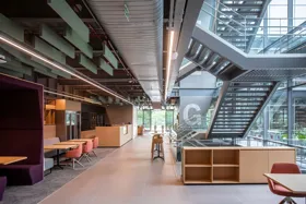 Modern office interior with open space, seating areas, and a staircase