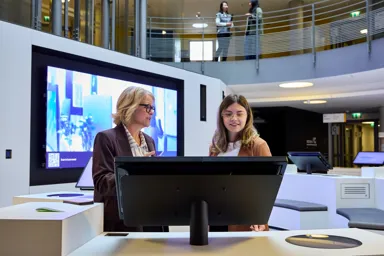 Two women discussing at an interactive display in a modern office environment