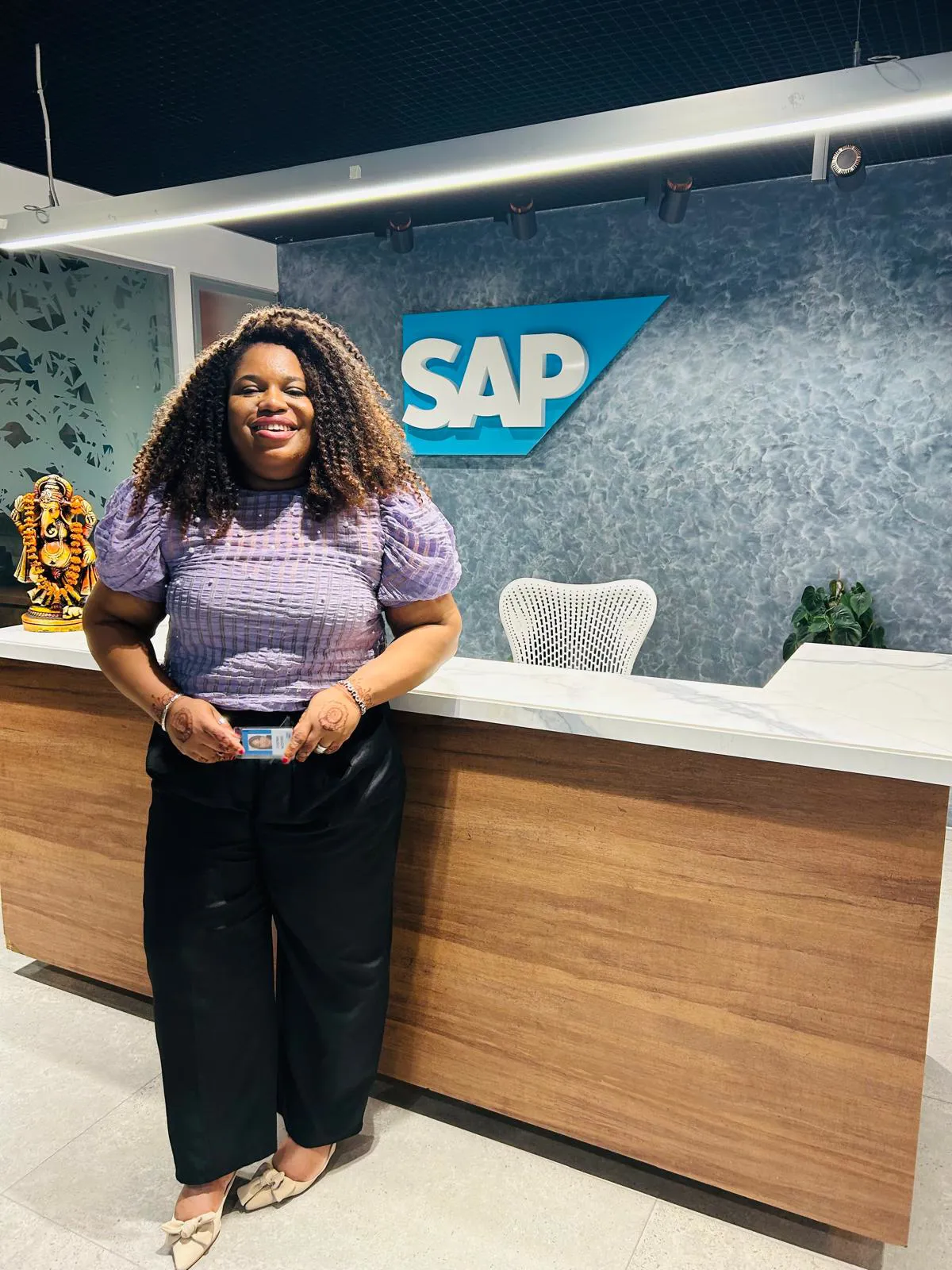 Chioma smiling in front of the reception desk at an SAP office
